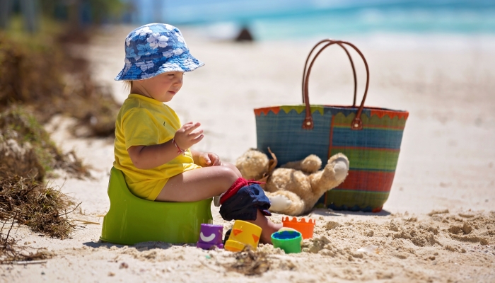 Little toddler boy, learning potty training on the beach on a tropical island.