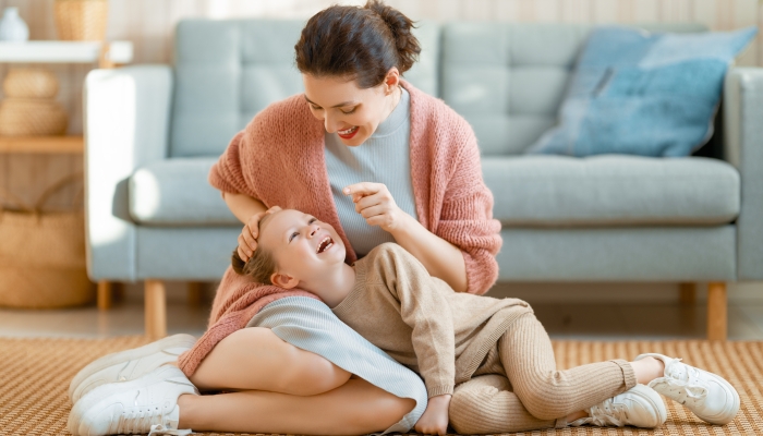 Mom and her daughter child girl are playing, smiling and hugging at home.