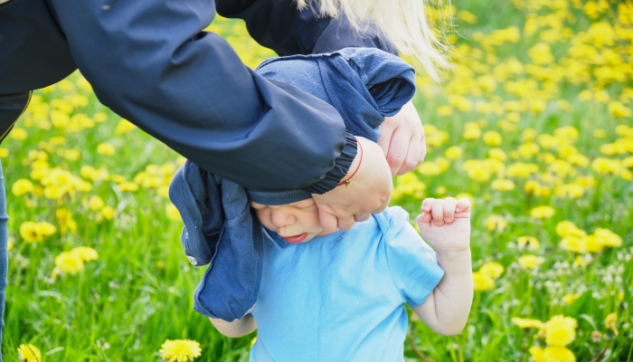 Mother trying to put a sweater on a child with special needs.