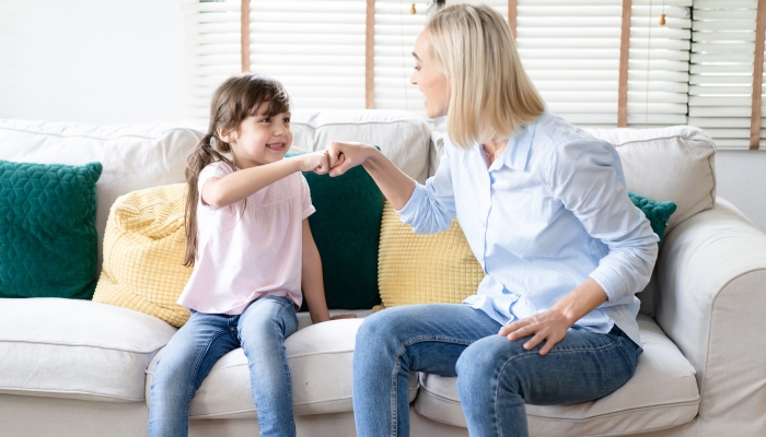 Portrait of happy smiling mother and daughter with pleasant smile greet happily and give fist bump.