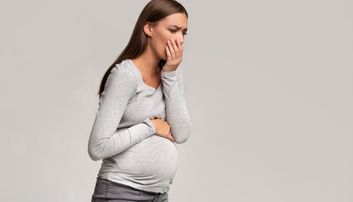 Pregnant Lady Feeling Sick Having Nausea Standing On Gray Studio Background.