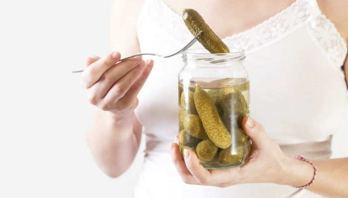 Pregnant woman holding jar of pickles.