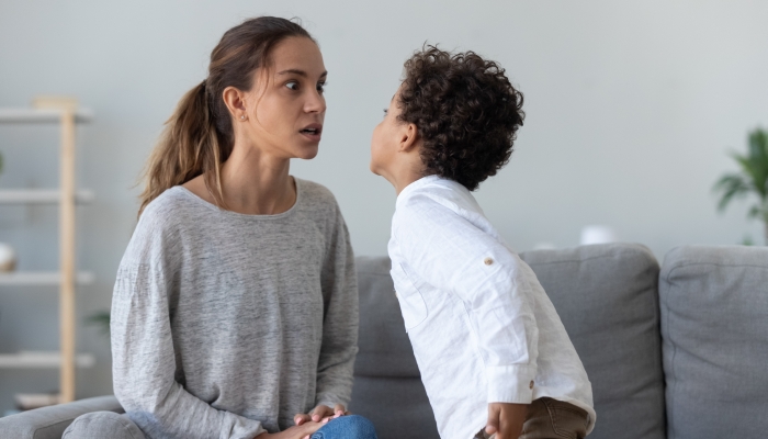 Provocative mixed race little kid demonstrating impolite disrespectful behavior to angry mother.