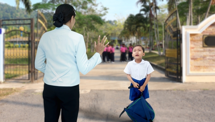 Schoolboy who crying with mother because he don't want go to school.