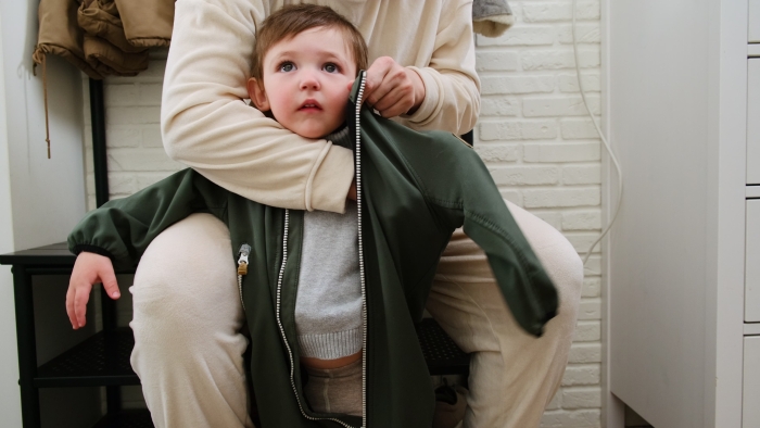 The mother puts a thermal jumpsuit on her child to keep them warm in the cold weather.