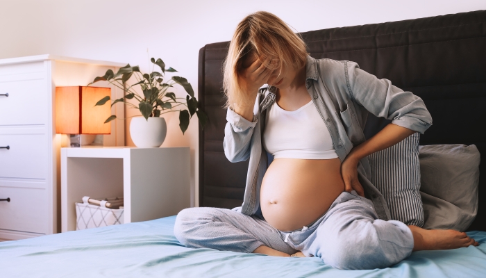 Woman getting a contraction and backache at home.