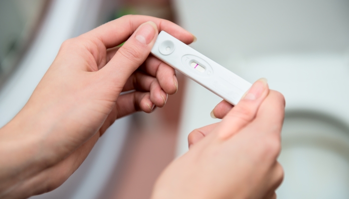 Woman holding negative pregnancy test.