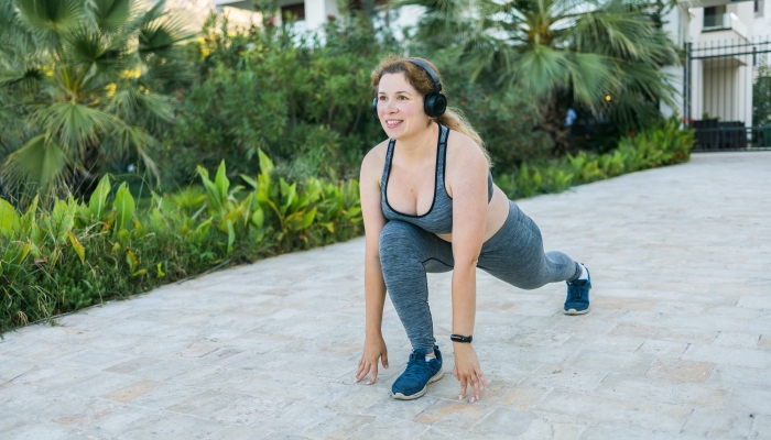 Young pretty smiling plus size woman in sporty top and leggings doing sport fitness.