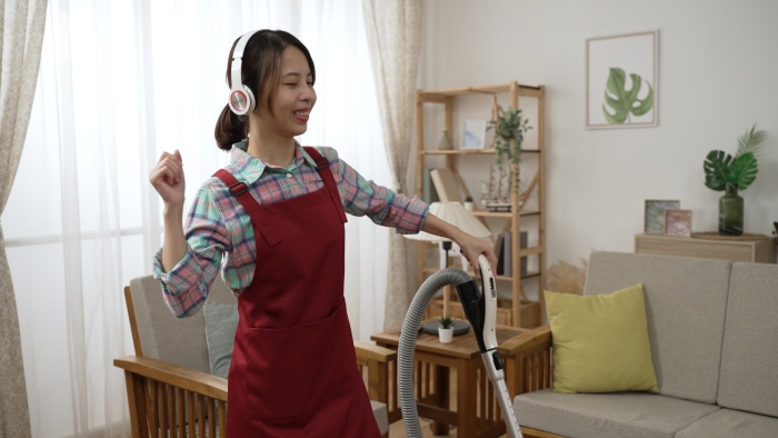 Young wife dancing with vacuum cleaner and having fun during doing housework.