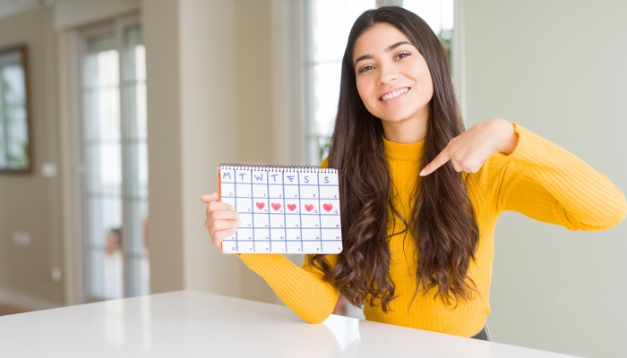 Young woman holding menstruation calendar.