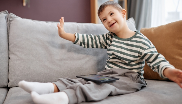 Cute little boy with down syndrome using imagination while playing mobile games.