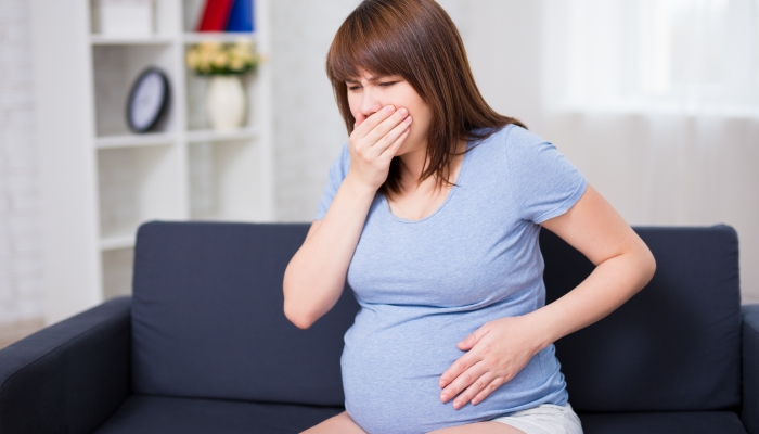 young pregnant woman suffering with nausea at home.
