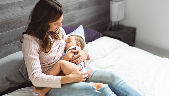 A Young woman breastfeeding her baby at home.