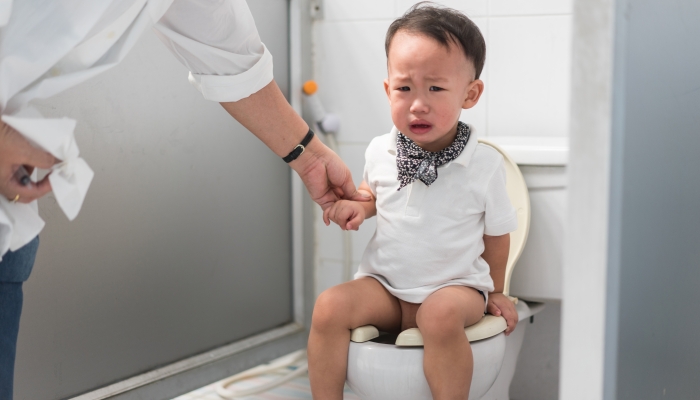 A boy is sitting on toilet with suffering from constipation.