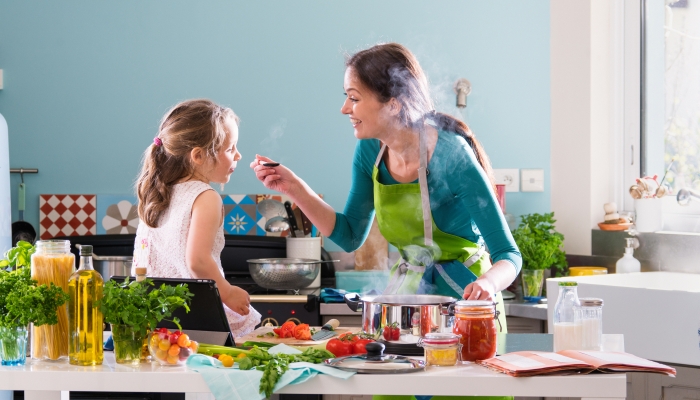 A young mother and her little daughter cooking.