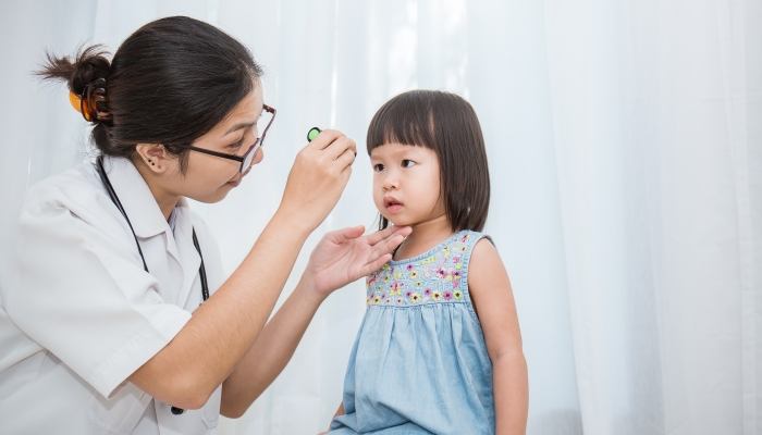 Asian doctor woman examine eyes of little asian girl in the clinic.