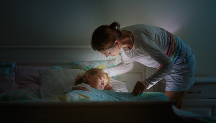 Child sleeping in dark bedroom with a night light.