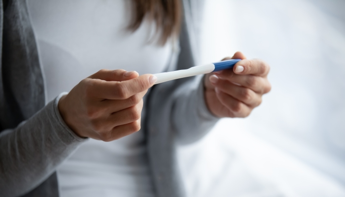 Close up cropped image woman holding plastic pregnancy test kit in hands.