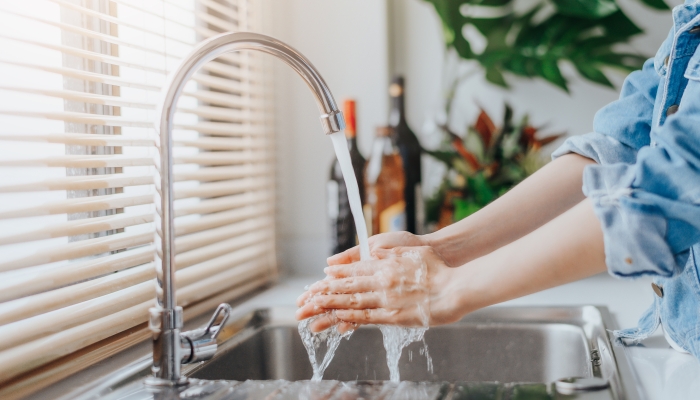 Close up shot of woman washing hands in sink before cooking at home kitchen.