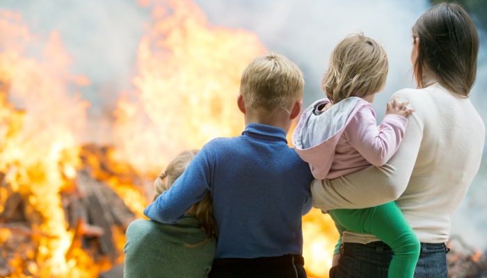 Family mother with children at burning house fire accident background.