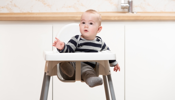 Happy Baby Sitting in High Chair in a White Kitchen.
