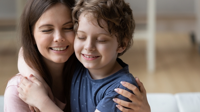 Head shot smiling mother and little son touching cheeks with closed eyes.