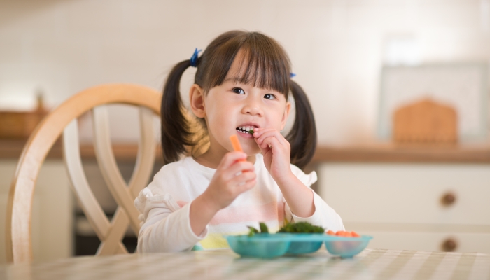 Little girl eating carrots.