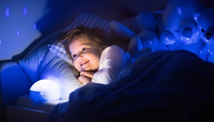 Little girl reading a book in bed.