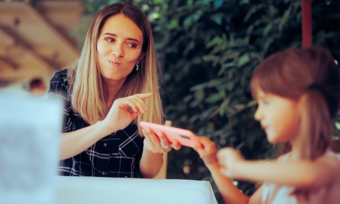 Mom taking away technology gadgets at the table.