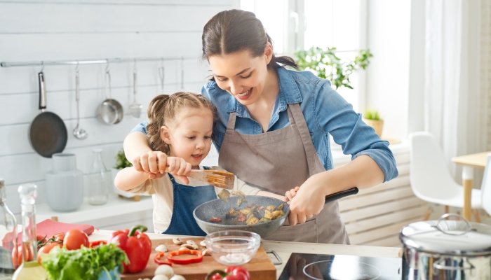 A young mothMother and child daughter are preparing proper meal.er and her little daughter cooking.