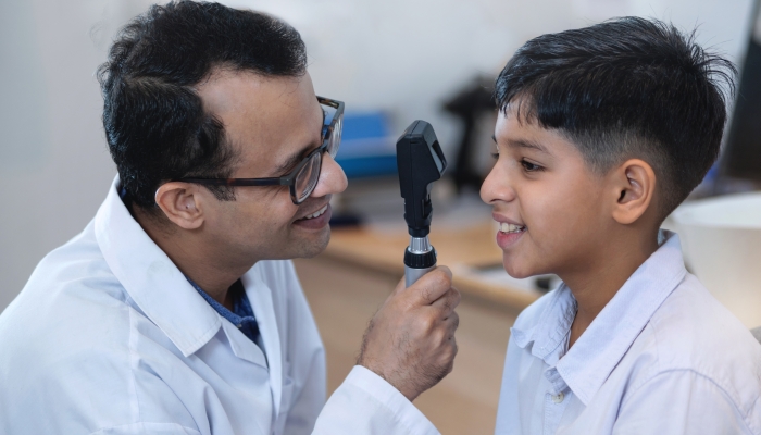 Optometrist is examining the eyes of an Indian boy.