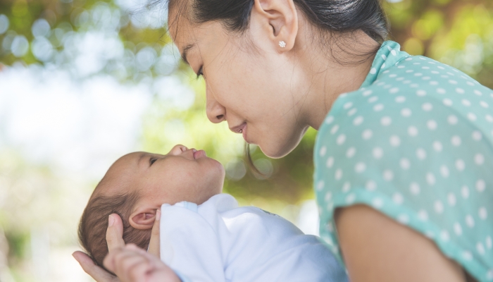 Portrait of a Woman holding her baby girl outdoor.