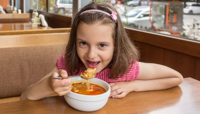 Portrait of a beautiful young girl eating mature bean at a restaurant.