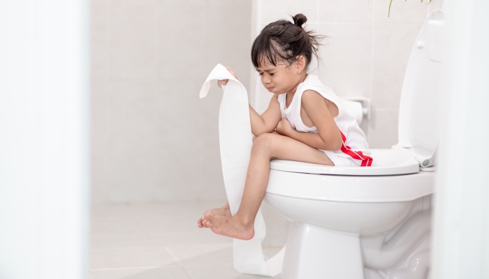 The little girl is sitting on the toilet suffering from constipation or hemorrhoid.