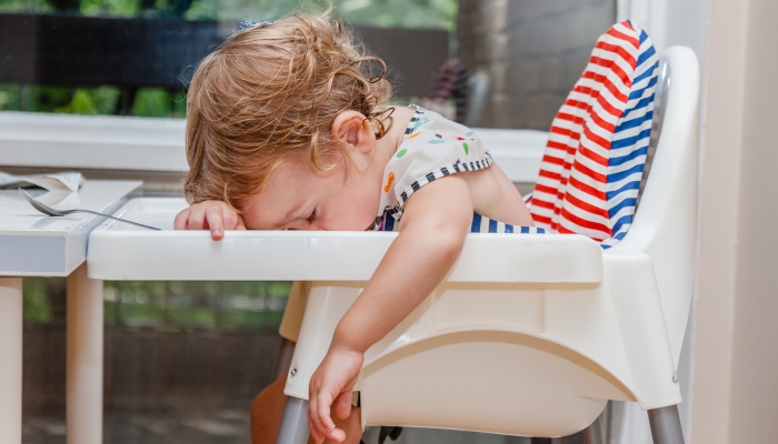 Tired child sleeping in highchair after the lunch.