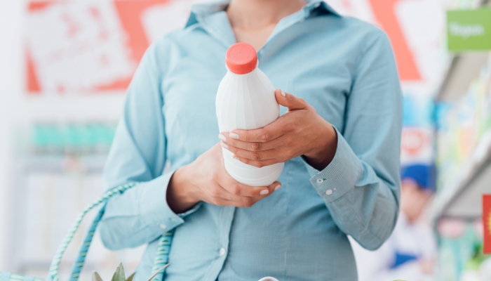 Woman doing grocery shopping at the supermarket and reading food labels.