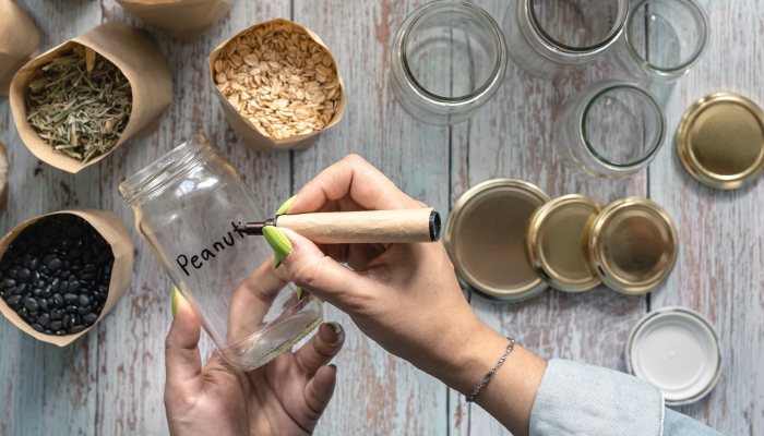 Woman hand labelling recycled glass jar for bulk food.