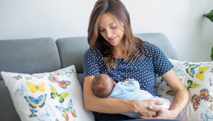 Young mother breastfeeding her newborn baby boy at home.