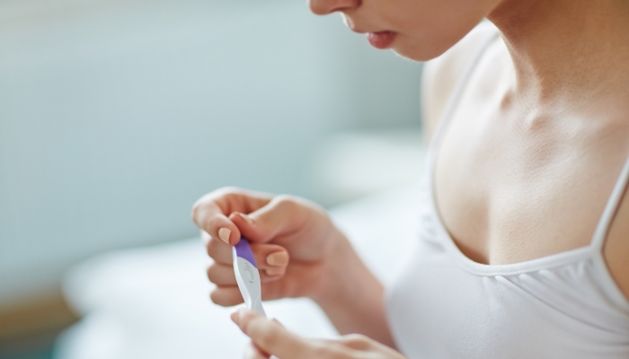 Young woman with pregnancy test in hands.