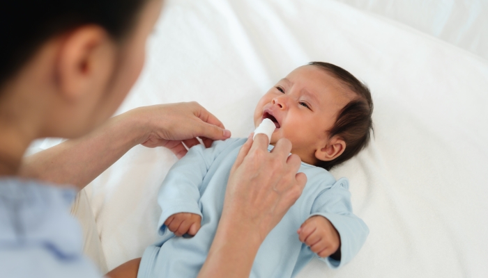 Mother using finger to clean newborn baby mouth.