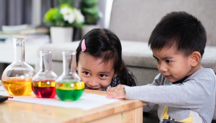 Asian 5 years old student and little brother looking to oil and water separation for liquid density science experiment.