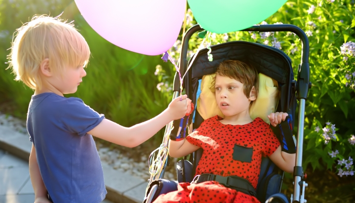 Brother hands balloons to sister.