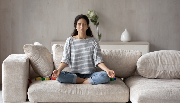 Calm Latino woman sit relax on sofa at home.