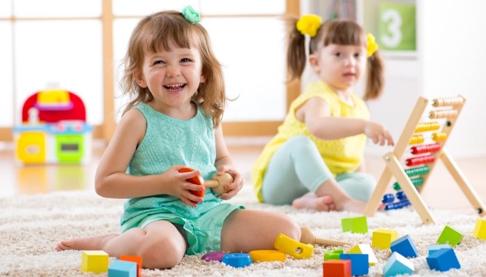 Children toddlers girls play logical toy learning shapes, arithmetic and colors at home.