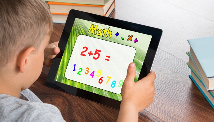 Close-up Of Boy Solving Math Problem On Digital Tablet In Classroom.
