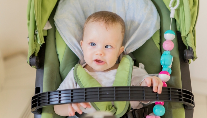 Close up of cute baby girl looking at the camera while sitting in the stroller.