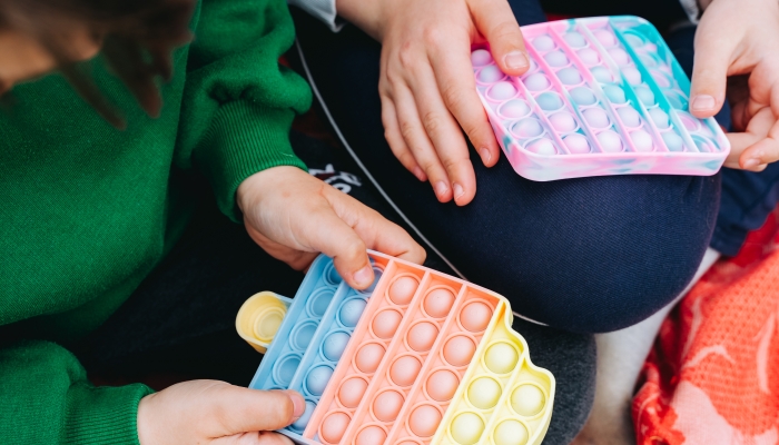 Close up on children Siblings playing with colorful poppit sensory game.