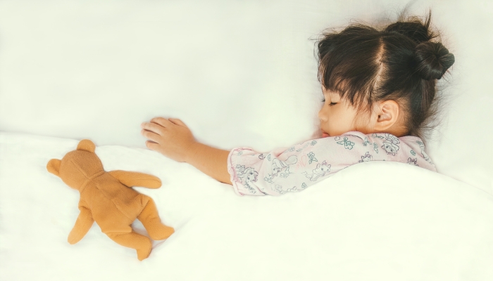 Cute asian child sleepping with her teddy bear.