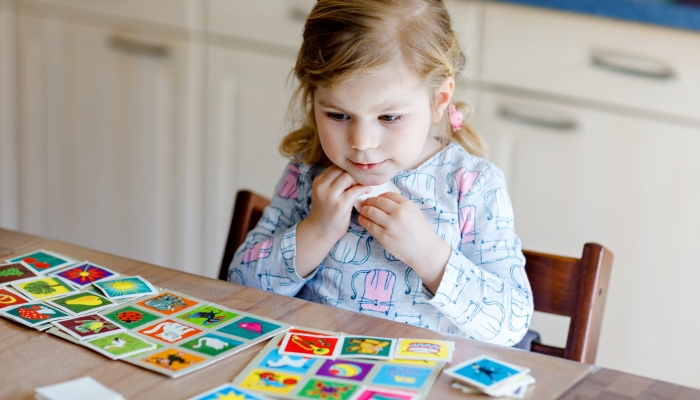 Excited smiling cute toddler girl playing picture card game.