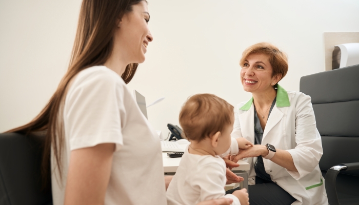 Friendly eye doctor providing initial consultation to female parent with baby.